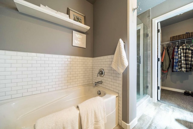 full bath with wood finished floors, baseboards, a walk in closet, a bath, and a shower stall