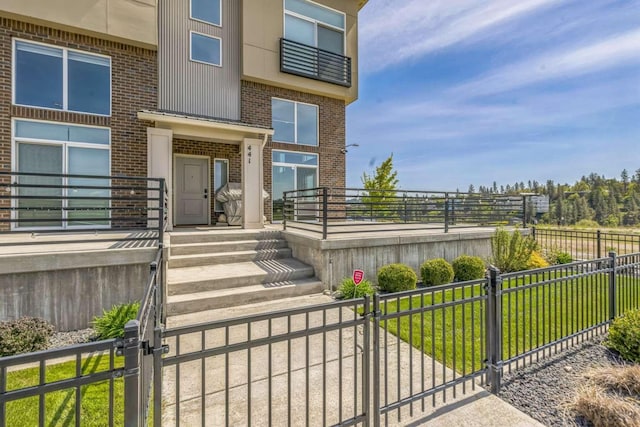 property entrance featuring fence, a gate, a yard, and brick siding