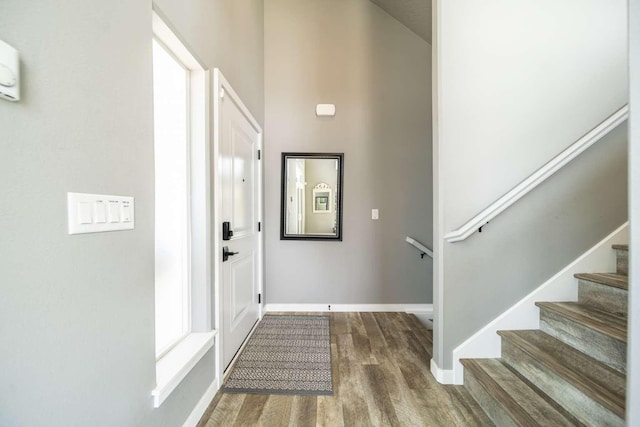 entryway featuring baseboards, stairs, and wood finished floors