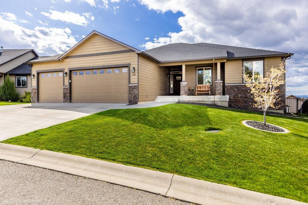 6025 N Hillmont Ln, Spokane, WA 99217 - view of front of property featuring an attached garage, a front lawn, stone siding, a porch, and concrete driveway