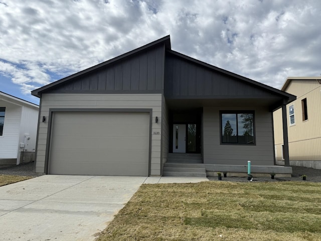view of front of house with an attached garage, driveway, a front yard, and covered porch