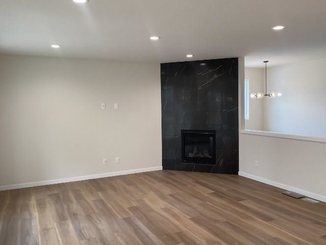 unfurnished living room with recessed lighting, baseboards, wood finished floors, and a fireplace
