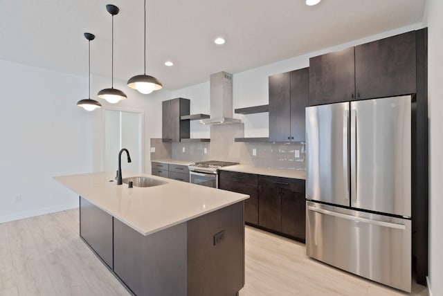 kitchen with dark brown cabinetry, light wood-type flooring, a sink, stainless steel appliances, and wall chimney exhaust hood