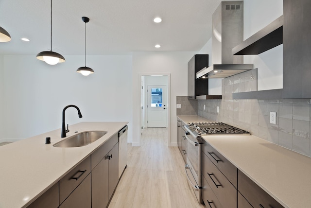 kitchen featuring light countertops, a sink, wall chimney range hood, and stainless steel appliances