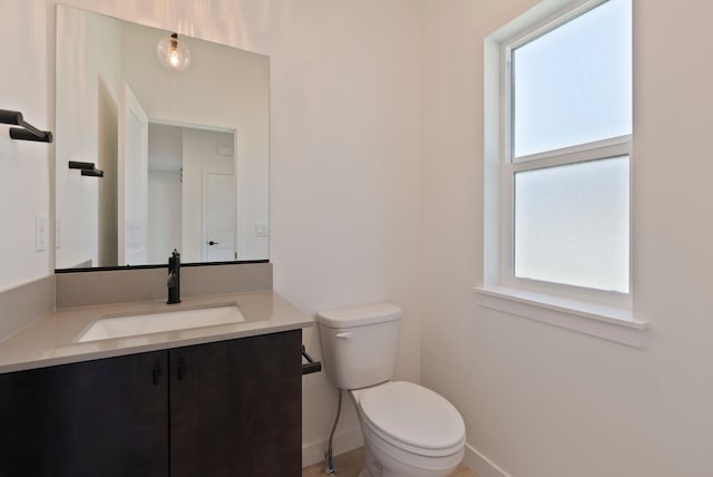 bathroom featuring baseboards, toilet, and vanity