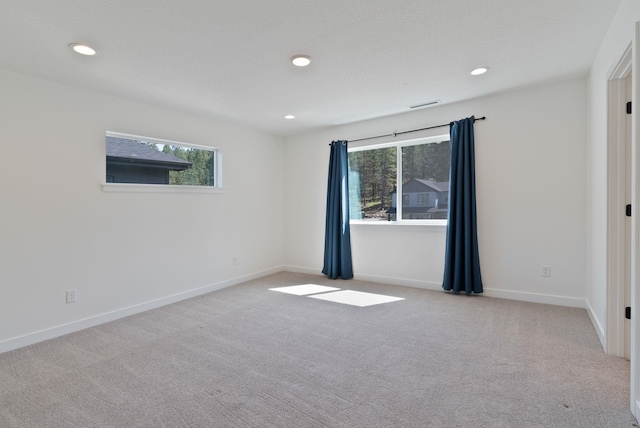 carpeted empty room featuring baseboards, recessed lighting, and visible vents