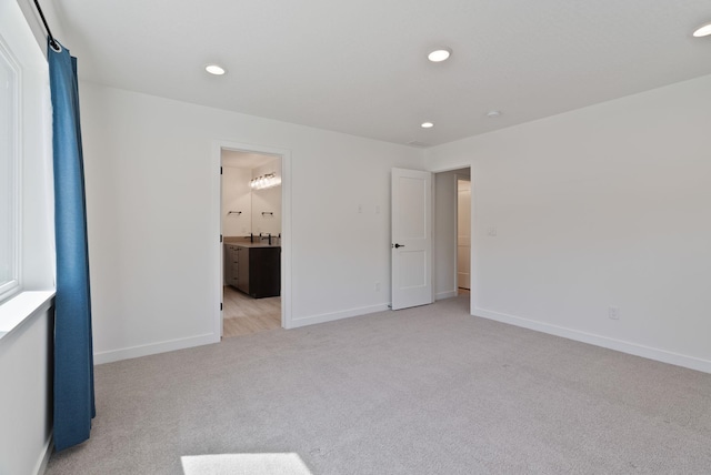 unfurnished bedroom featuring baseboards, ensuite bathroom, recessed lighting, and light colored carpet