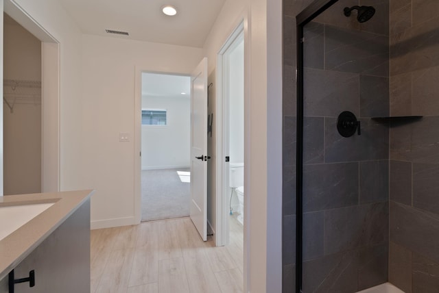bathroom featuring vanity, toilet, a shower stall, wood finished floors, and visible vents
