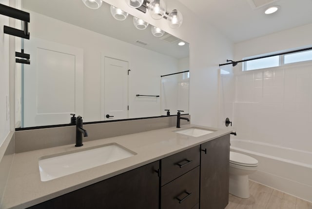 bathroom featuring a sink, shower / bathing tub combination, toilet, and double vanity
