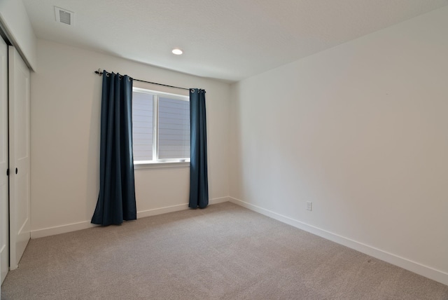 unfurnished bedroom with baseboards, light colored carpet, visible vents, and a closet