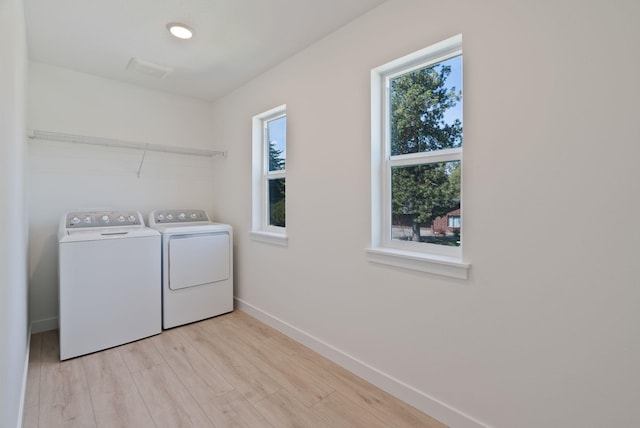 washroom featuring laundry area, light wood-type flooring, baseboards, and washing machine and clothes dryer