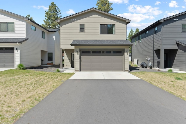 traditional-style home with a garage, a front yard, and aphalt driveway