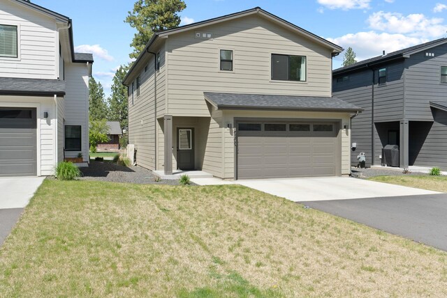 traditional-style home featuring a garage, driveway, and a front lawn
