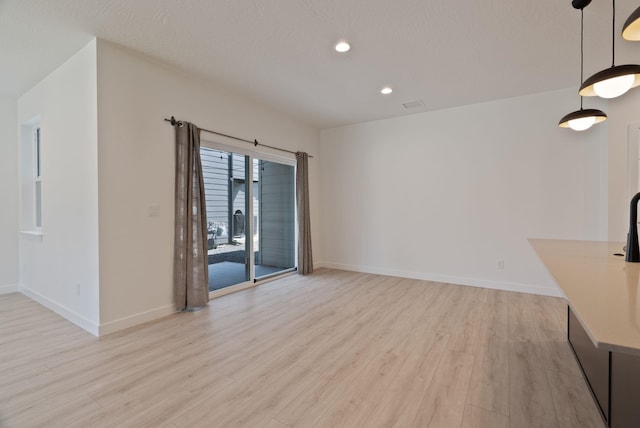 unfurnished living room featuring recessed lighting, baseboards, and light wood finished floors