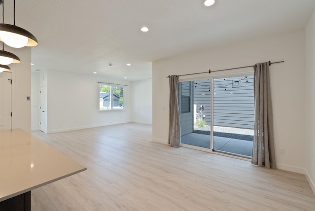 unfurnished living room featuring recessed lighting, baseboards, and light wood-style flooring
