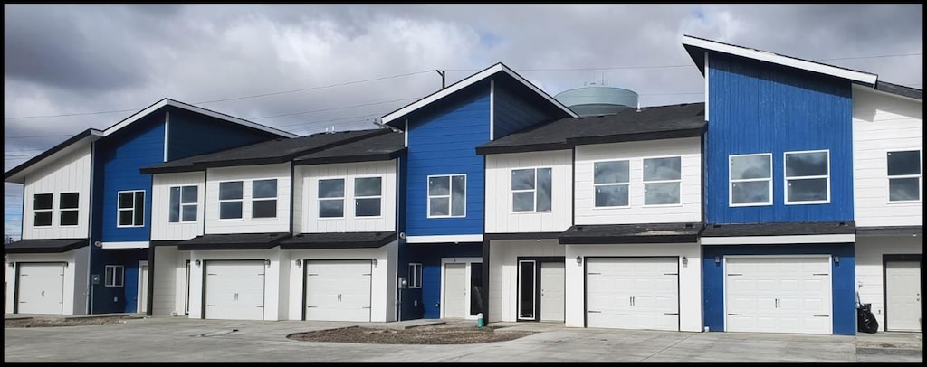 townhome / multi-family property featuring a garage, a shingled roof, and driveway