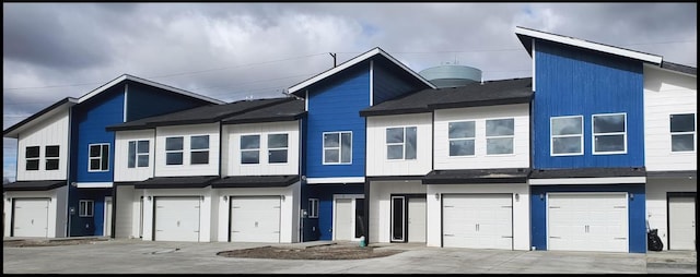 townhome / multi-family property featuring a garage, a shingled roof, and driveway