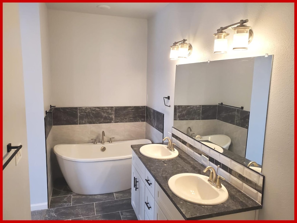 bathroom featuring a sink, double vanity, and a freestanding bath