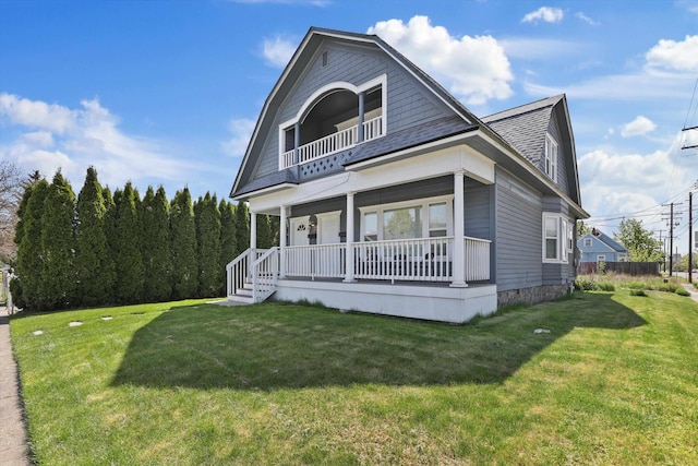 view of front facade featuring a front yard, a porch, a gambrel roof, and a balcony