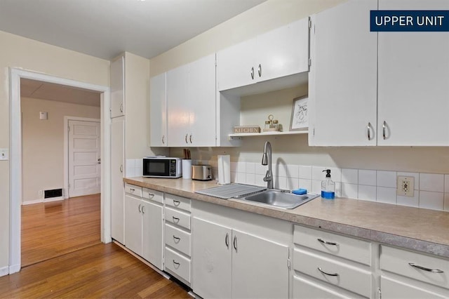 kitchen featuring white range with electric cooktop, light wood-style floors, white cabinets, electric panel, and a sink