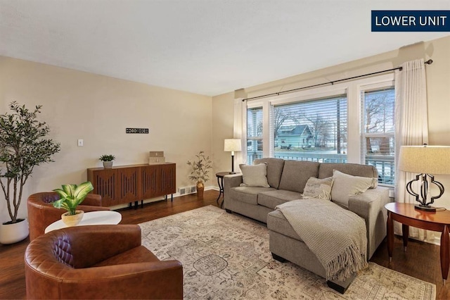 living area featuring baseboards, wood finished floors, and visible vents