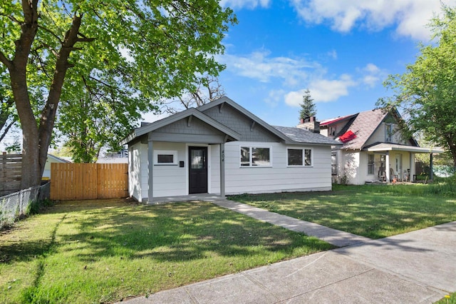 bungalow featuring a front lawn and fence