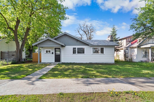 bungalow featuring a front lawn, fence, and a chimney