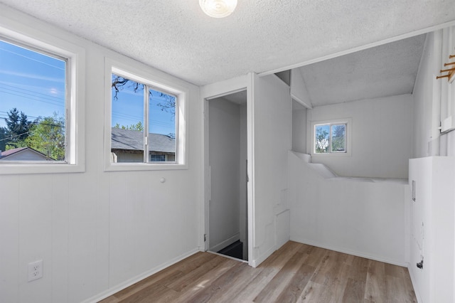 interior space featuring a textured ceiling, baseboards, and wood finished floors