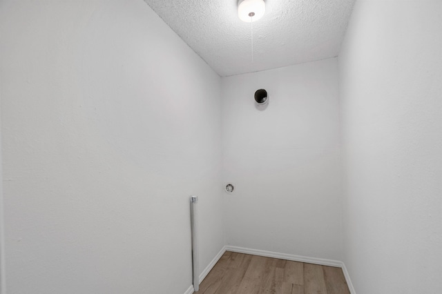 washroom with laundry area, a textured ceiling, light wood finished floors, and baseboards
