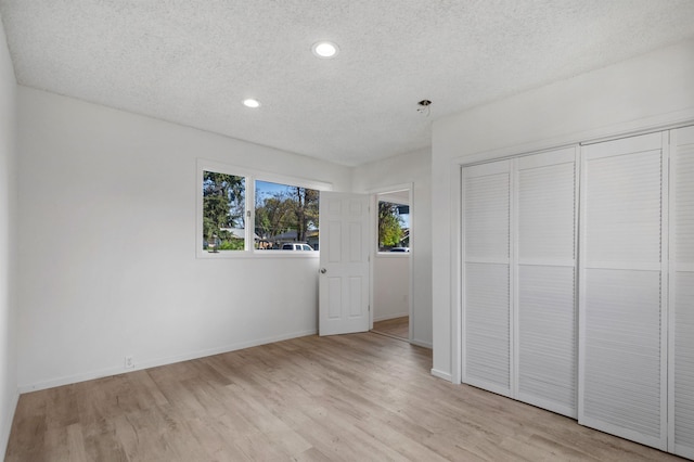 unfurnished bedroom with light wood finished floors, a textured ceiling, recessed lighting, baseboards, and a closet