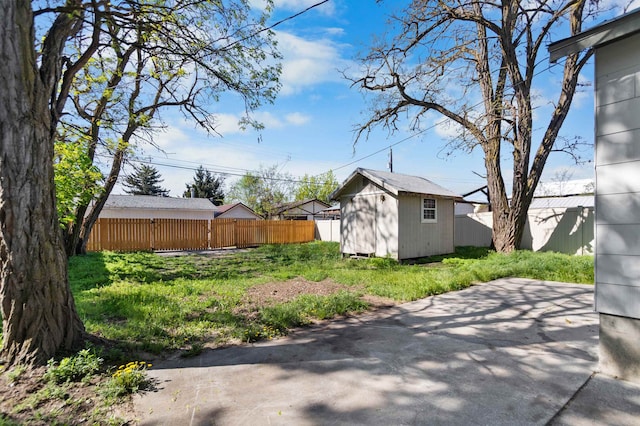view of yard featuring fence, an outdoor structure, a patio area, and a storage unit