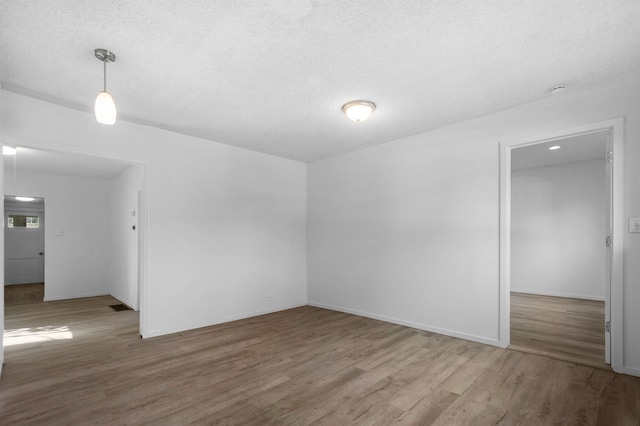 spare room with baseboards, a textured ceiling, visible vents, and wood finished floors