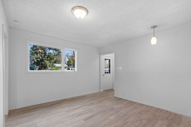 empty room with a textured ceiling, baseboards, and wood finished floors