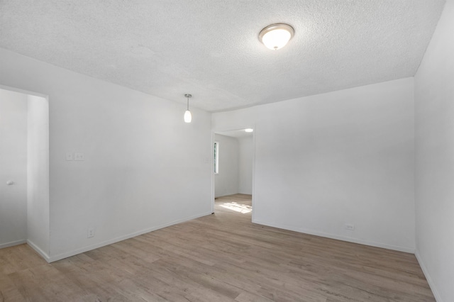 spare room with baseboards, a textured ceiling, and wood finished floors