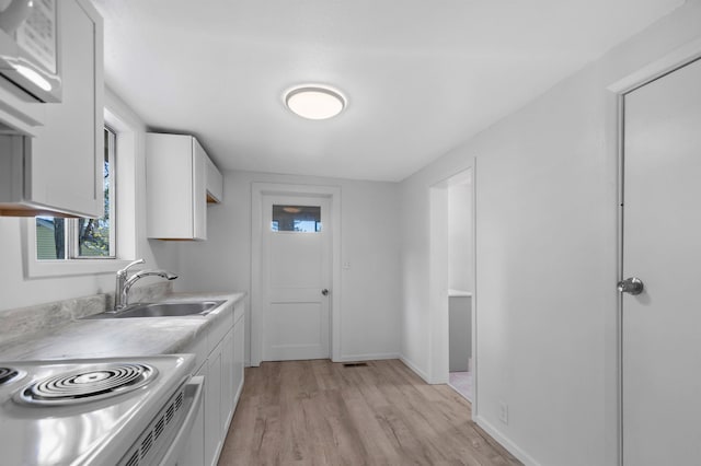 interior space with baseboards, a sink, light wood-style flooring, and visible vents