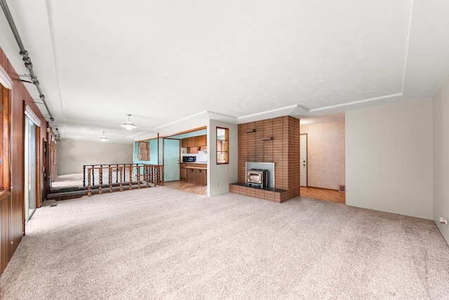 unfurnished living room featuring carpet and a wood stove