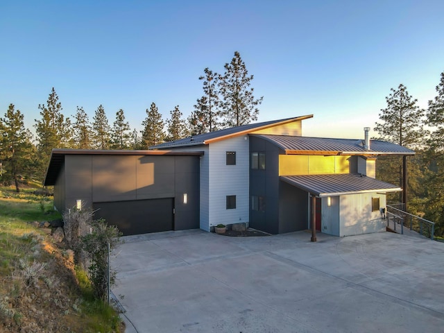 view of front of house with a standing seam roof, driveway, metal roof, and a garage