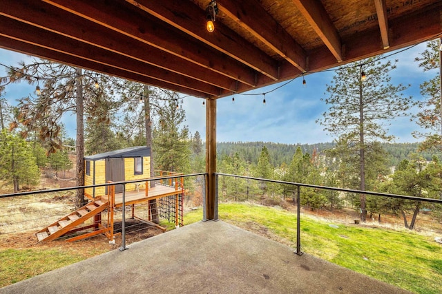 exterior space featuring an outdoor structure, fence, a storage unit, and a forest view