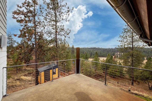 view of patio / terrace featuring a view of trees and a balcony
