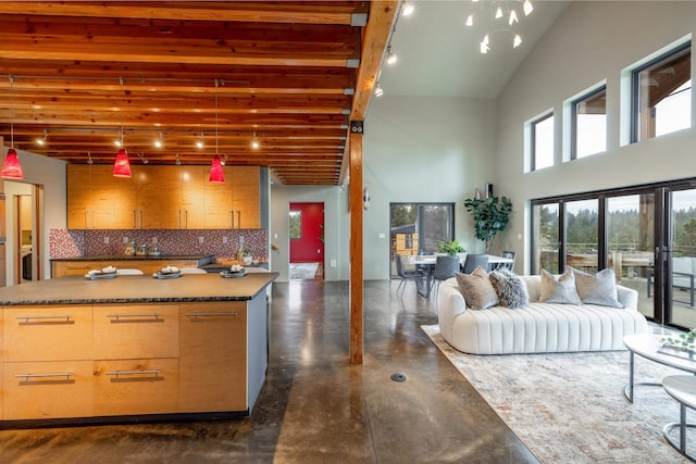 kitchen featuring finished concrete flooring, a center island, dark countertops, open floor plan, and a high ceiling