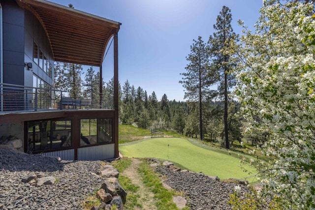 view of yard featuring a sunroom, view of golf course, and a balcony