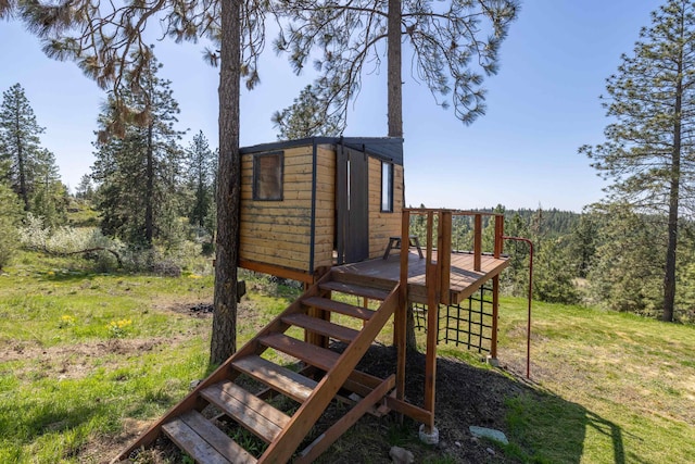 exterior space featuring an outdoor structure, stairway, a wooden deck, and a wooded view