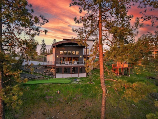 back of house at dusk featuring a balcony
