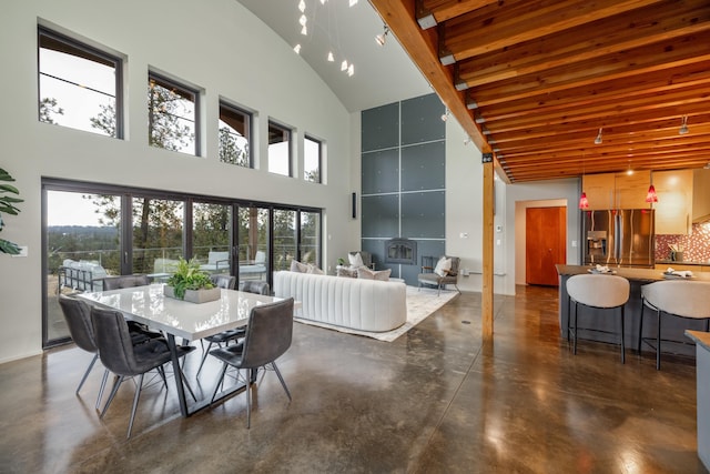 dining room with plenty of natural light, concrete flooring, and a high ceiling