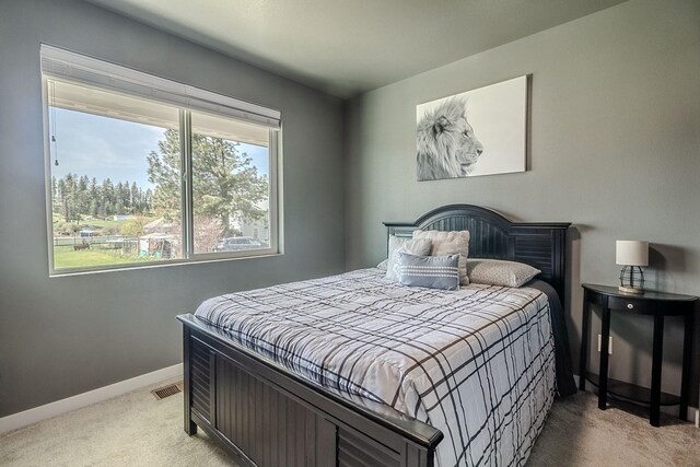 bedroom featuring baseboards, light colored carpet, and visible vents