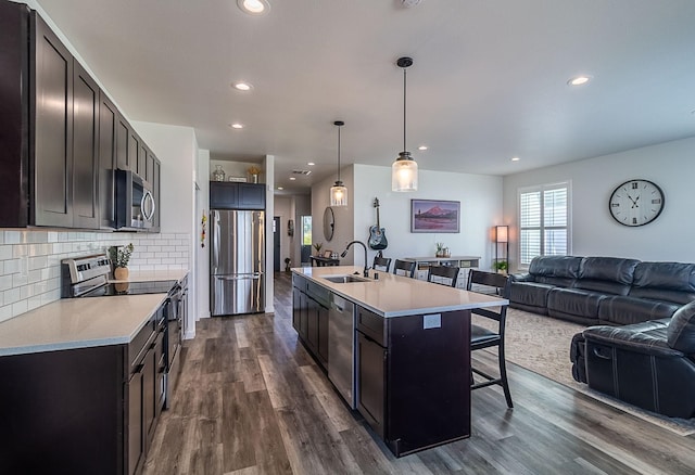 kitchen featuring a sink, a breakfast bar area, light countertops, stainless steel appliances, and open floor plan