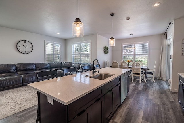 kitchen with a sink, dark wood finished floors, open floor plan, decorative light fixtures, and stainless steel dishwasher