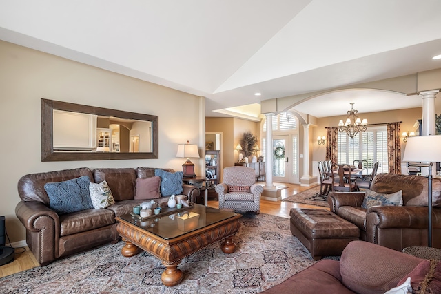 living room with ornate columns, arched walkways, a notable chandelier, and wood finished floors