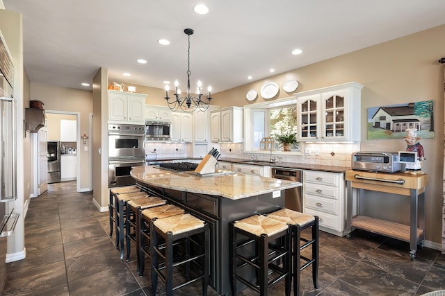 kitchen with a breakfast bar, an inviting chandelier, stainless steel appliances, backsplash, and a kitchen island