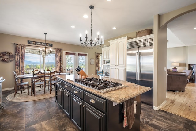 kitchen with white cabinets, dark cabinets, arched walkways, appliances with stainless steel finishes, and a notable chandelier
